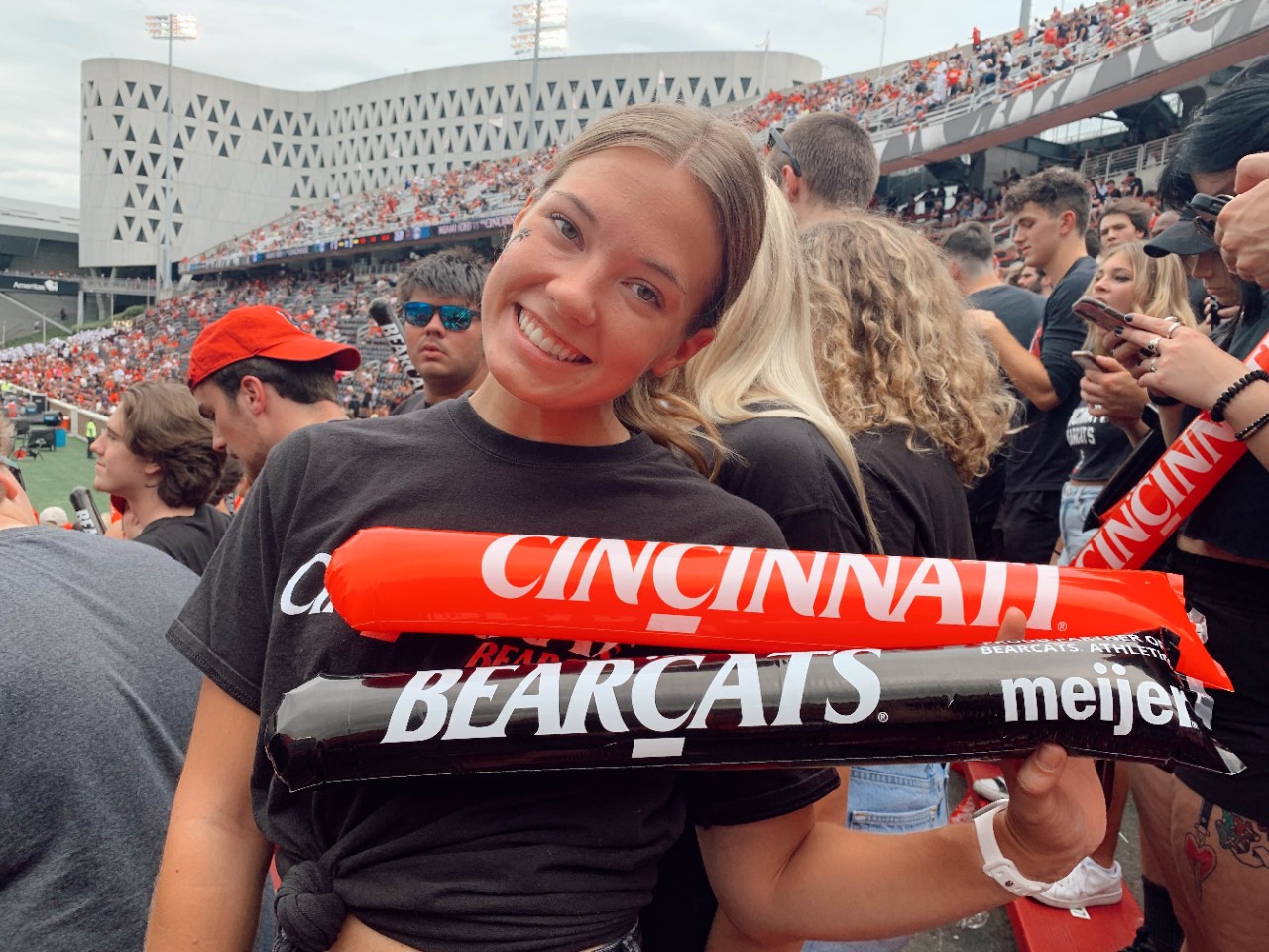 Mallory Hansen, 4th year Nutrition and Dietetics student holds two sticks. One says Cincinnati and the other says Bearcats.