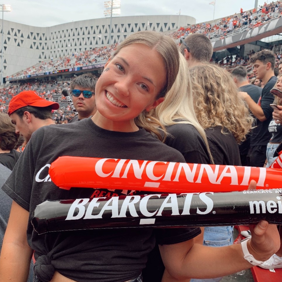Mallory Hansen, 4th year Nutrition and Dietetics student holds two sticks. One says Cincinnati and the other says Bearcats.