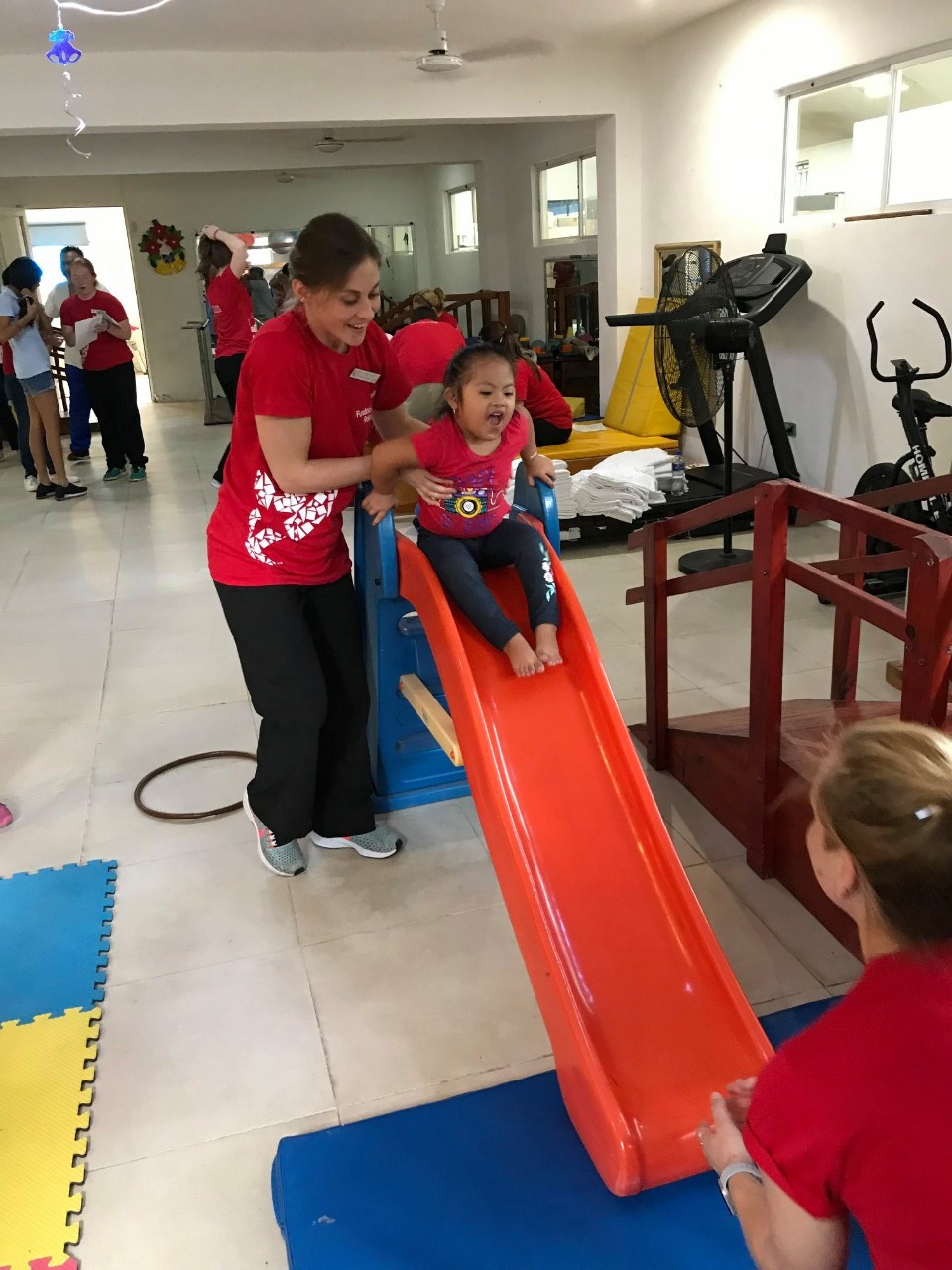PT student helps a child down the slide 